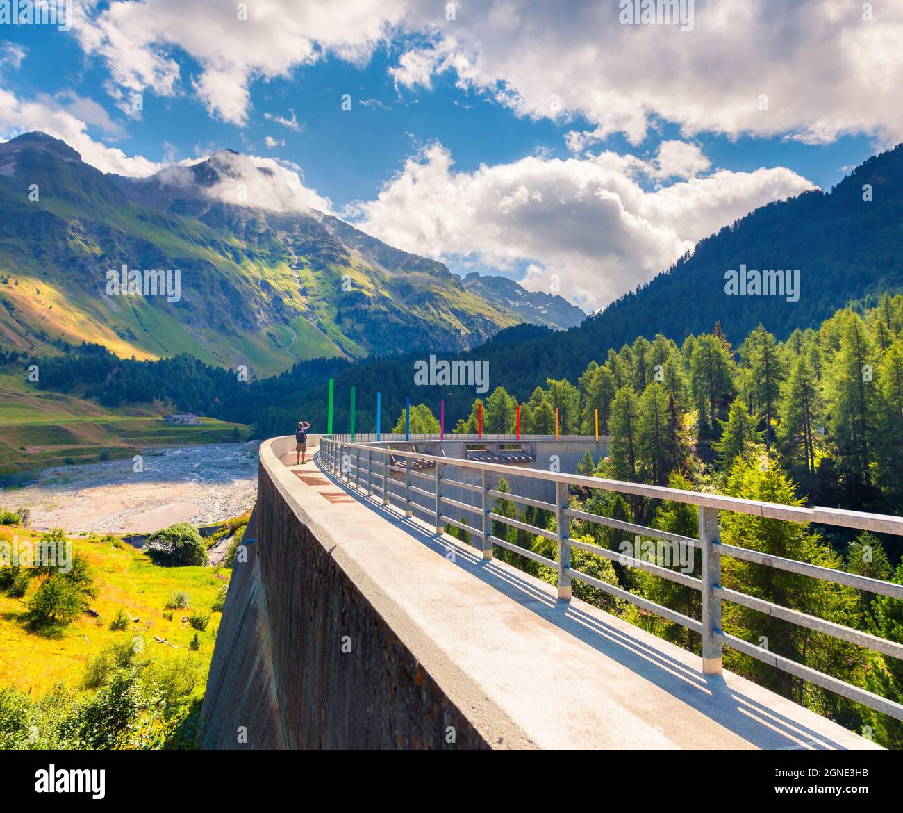 Il fotografo scatta una foto sulla diga sul fiume Orlegna. Soleggiata vista estiva dalla cima del passo Maloja. Alpi Svizzere, alta Engadina nel cantone dei Gri Foto Stock