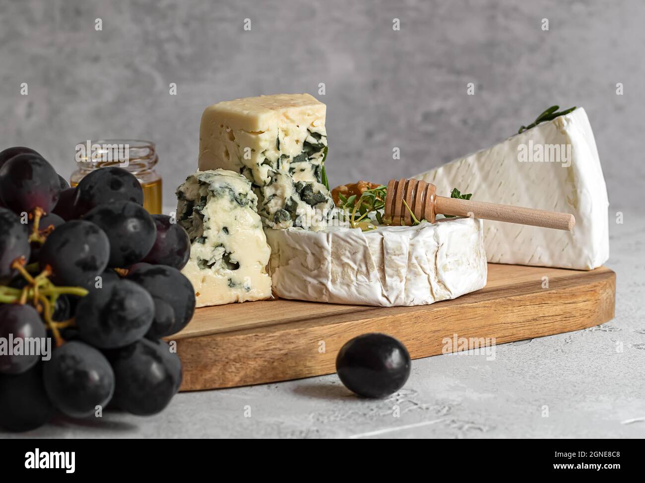 Camembert, Roquefort e brie con miele, uva e noci sul tagliere. Foto Stock