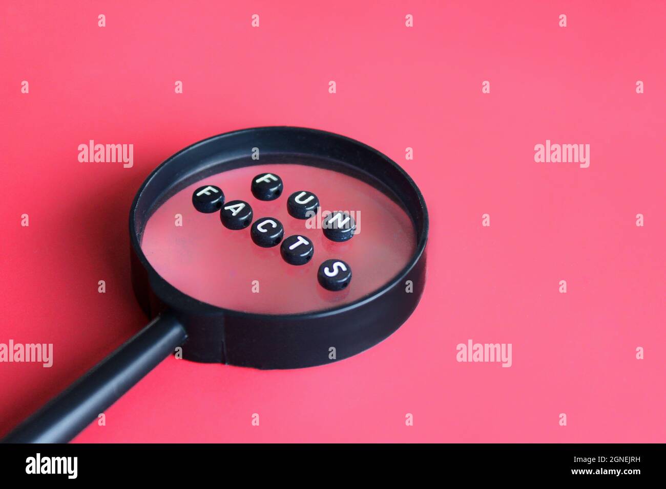 Lente d'ingrandimento e perle alfabetiche con testi DIVERTENTI FATTI Foto Stock