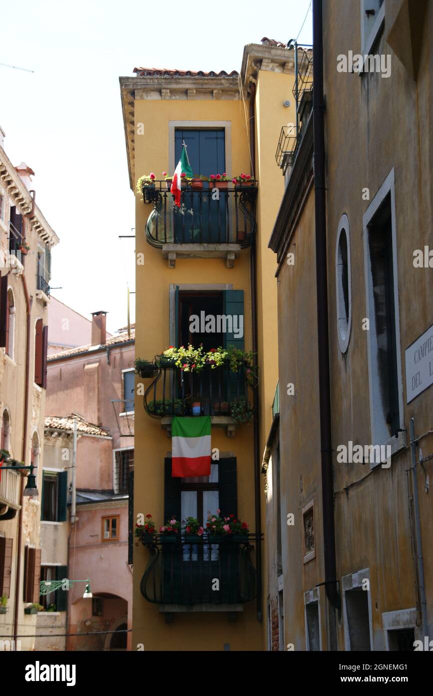 VENEZIA, ITALIA - 02 ago 2011: Un colpo verticale di bandiere d'Italia appese ai balconi di un edificio a Venezia Foto Stock