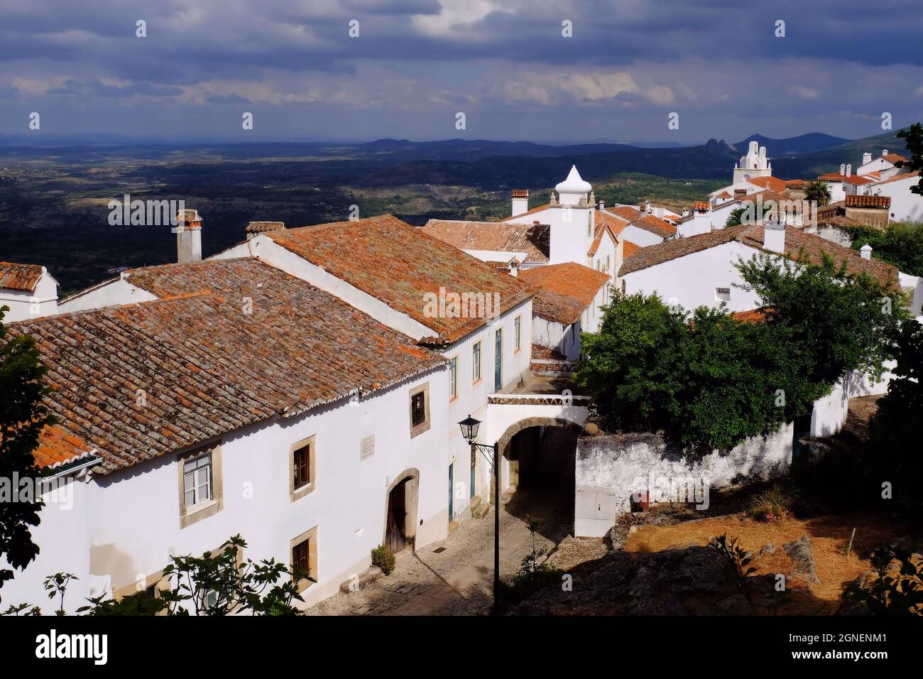 Arco ed edifici bianchi e luminosi della città con un cielo scuro poco prima del tramonto a Marvao, Alentejo, Portogallo Foto Stock