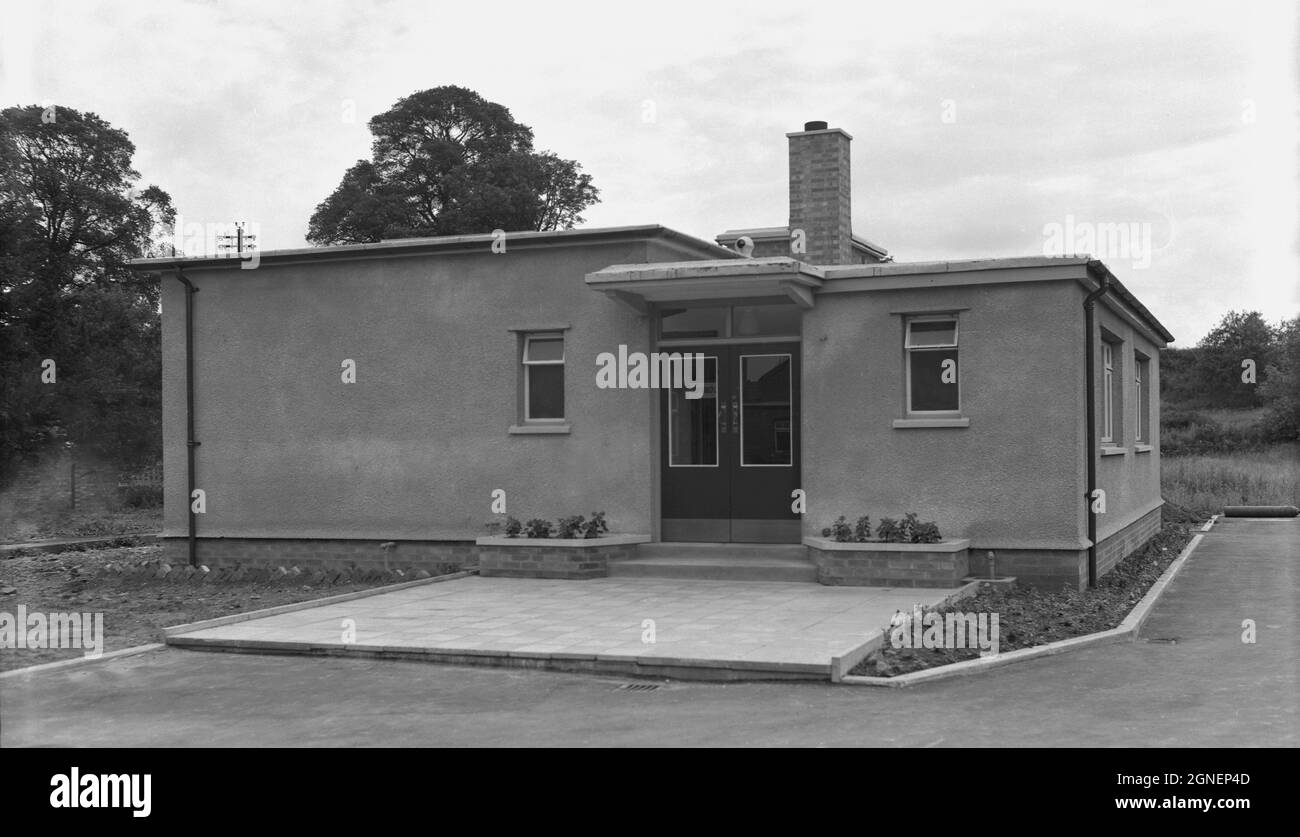 1960, storico, vista esterna di un nuovo edificio a un piano, con un rendering in cemento e un ampio ingresso lastricato, eventualmente un medico rurale ambulatorio o clinica sanitaria, Witney, Oxford, Inghilterra, Regno Unito. Foto Stock