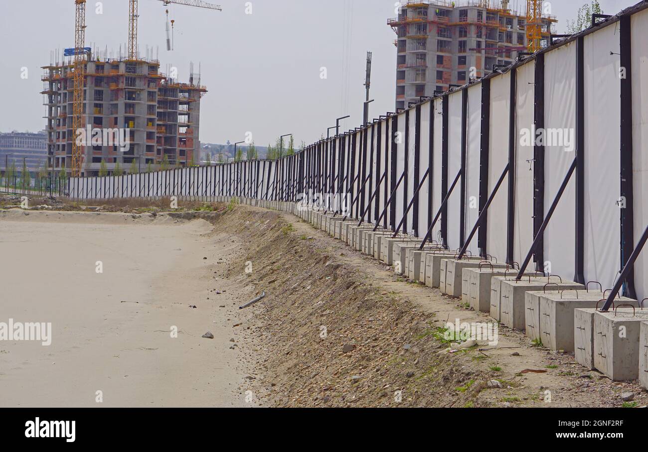 Recinzione temporanea con blocchi di calcestruzzo di sostegno in cantiere Foto Stock
