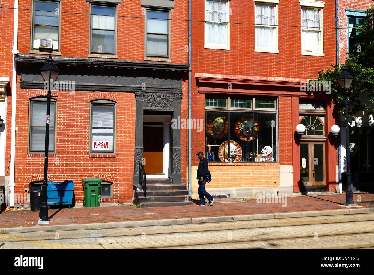 Afro americano uomo che cammina oltre A.T. Negozio di costumi Jones & Sons, N Howard St, Baltimora, Maryland, USA Foto Stock