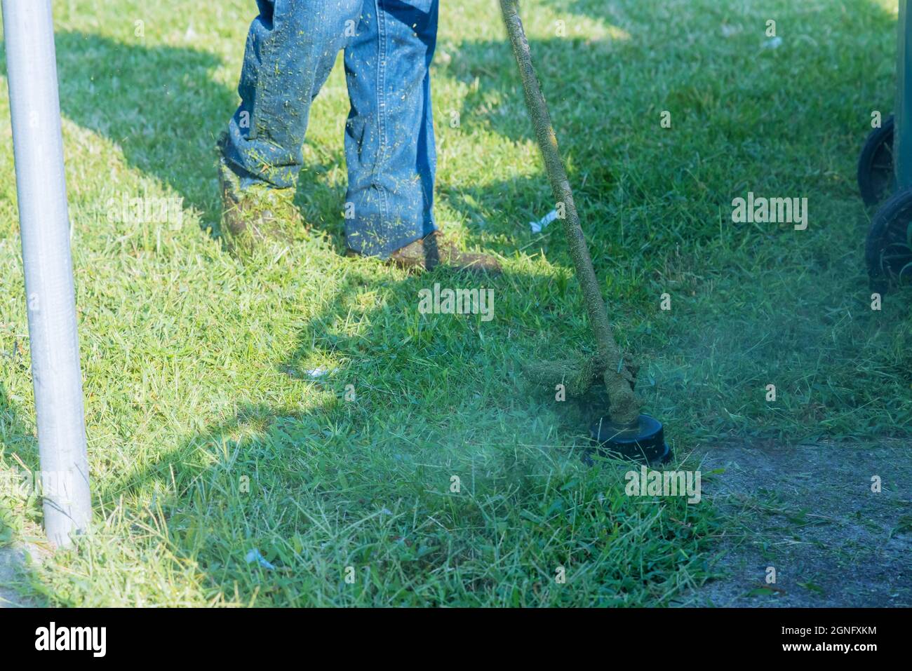 Un operaio di utilità in un prato verde con un prato che taglia l'erba Foto Stock