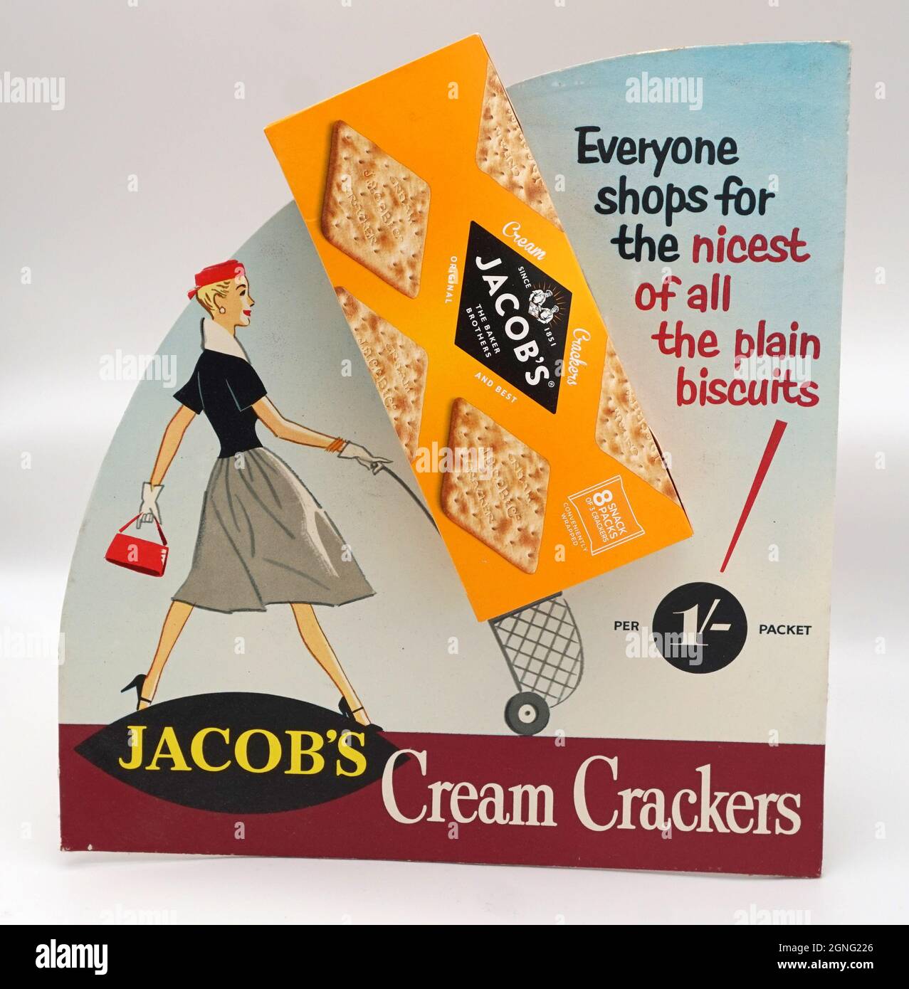 Jacob's Cream Crackers, questo stand vintage mostra pubblicitaria risale al 1950s. Prezzo per pacchetto 1/- (5p). Favolosa illustrazione di una donna moderna in stile anni '50 che spinge un carrello per lo shopping. "Tutti i negozi per il più bello di tutti i biscotti semplici". Foto Stock