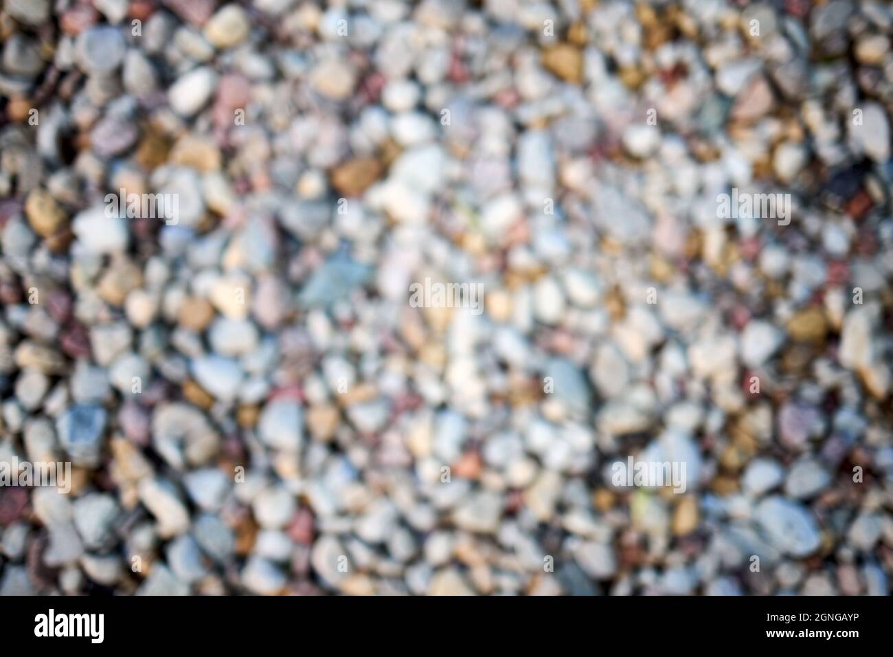 Calmo fiume spiaggia riva pietra astratta sfocatura. Sfondo astratto sfocato di ciottoli multicolore o pietre di ciottoli sul primo piano della riva. Sfocato Foto Stock