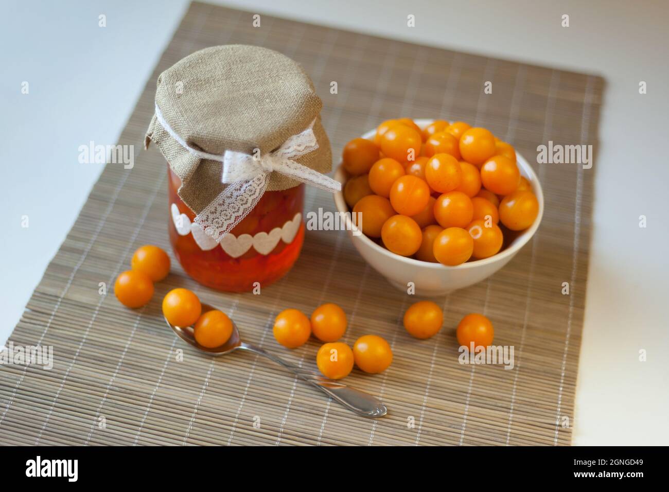 Prugne di ciliegia marmellata gialla, vitamine fresche-frutti di bosco. Marmellata fatta in casa in vaso di vetro sul marrone Foto Stock