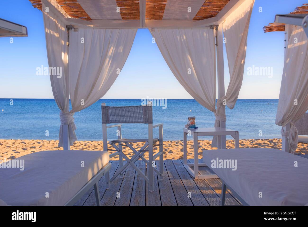 Canopie bianche: Sedie a sdraio sulla spiaggia. Tende da spiaggia di lusso in un resort in Puglia. Foto Stock