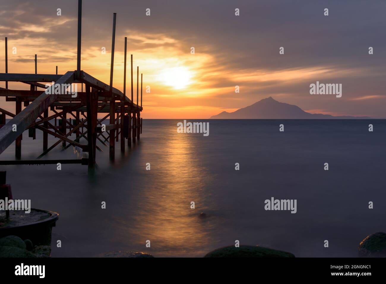 Il mare diventa una nuvola accanto ad un problema di ferro al tramonto sullo sfondo del sole e della penisola del Monte Athos Foto Stock