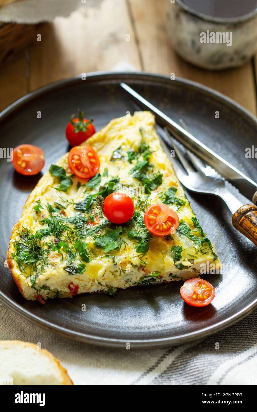Prima colazione di omelette con verdure, erbe e formaggio, servita con pane e caffè. Foto Stock