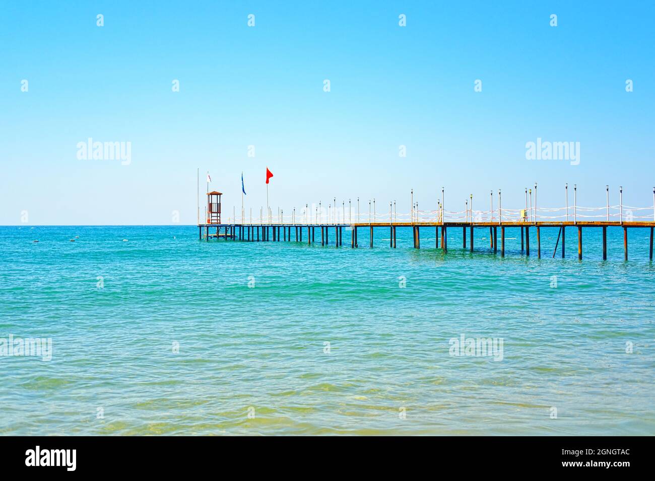 Onde sulla costa turchese di Manavgat Antalya e molo con bandiera turca Foto Stock