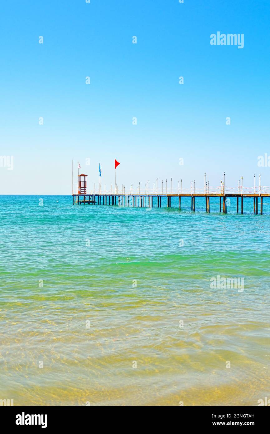 Onde sulla costa turchese di Manavgat Antalya e molo con bandiera turca Foto Stock