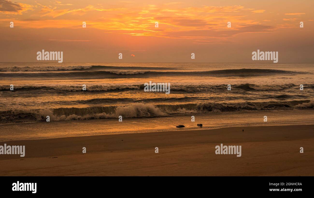 Cielo del mattino d'oro che si riflette nell'Oceano Atlantico e surf Foto Stock