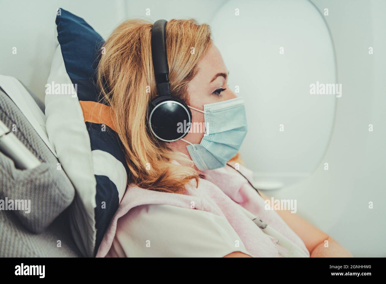 Caucasica Business Woman Travelling Business Class all'interno di un moderno aeromobile passeggeri durante i periodi pandemici. Ascoltare musica a bordo e guardare i Busines Foto Stock