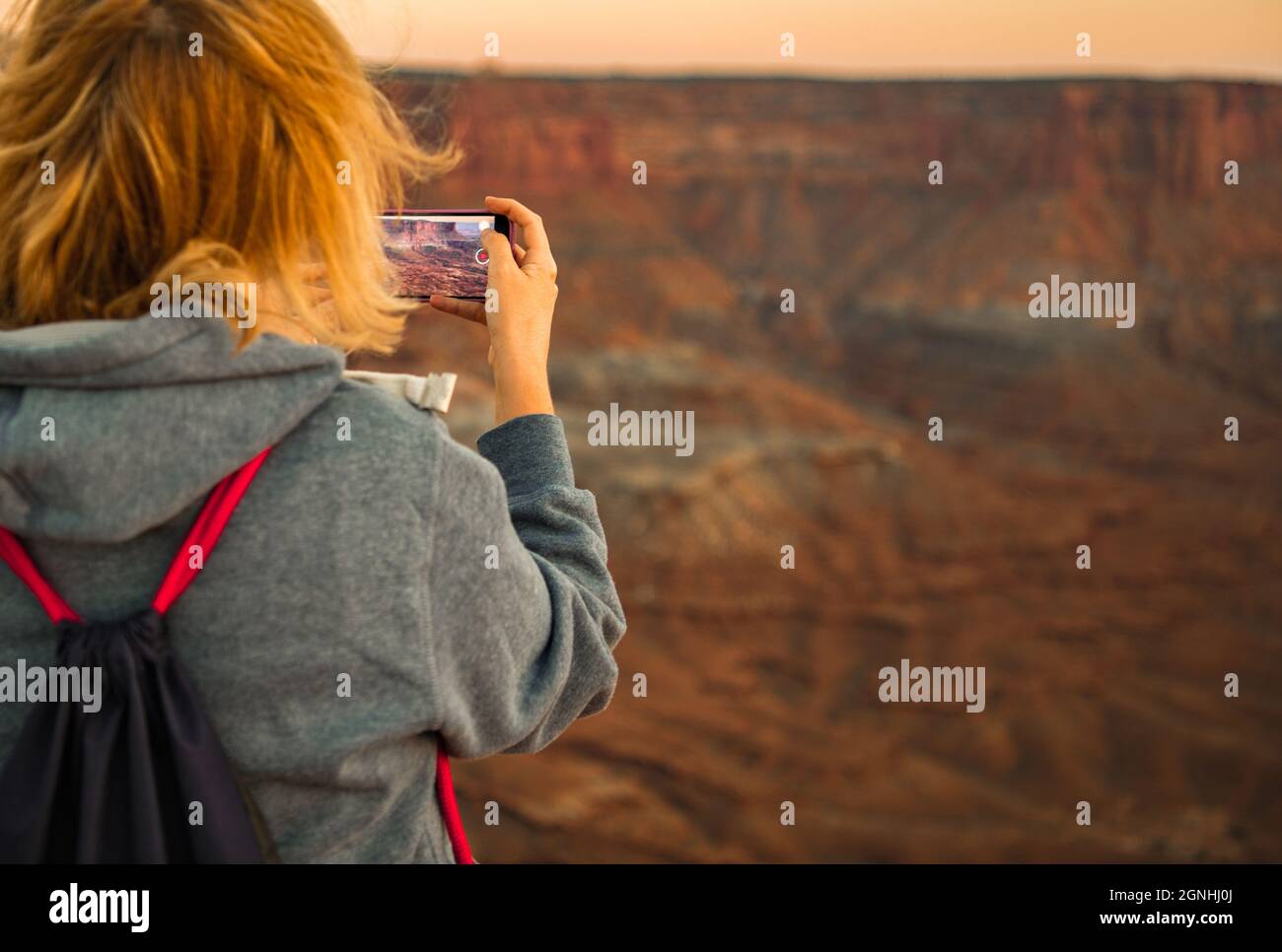 Donna caucasica nel suo 40s fare video usando il dispositivo moderno dello smartphone. Paesaggio panoramico delle Utah Canyonlands. Tema dei video di viaggio. Foto Stock