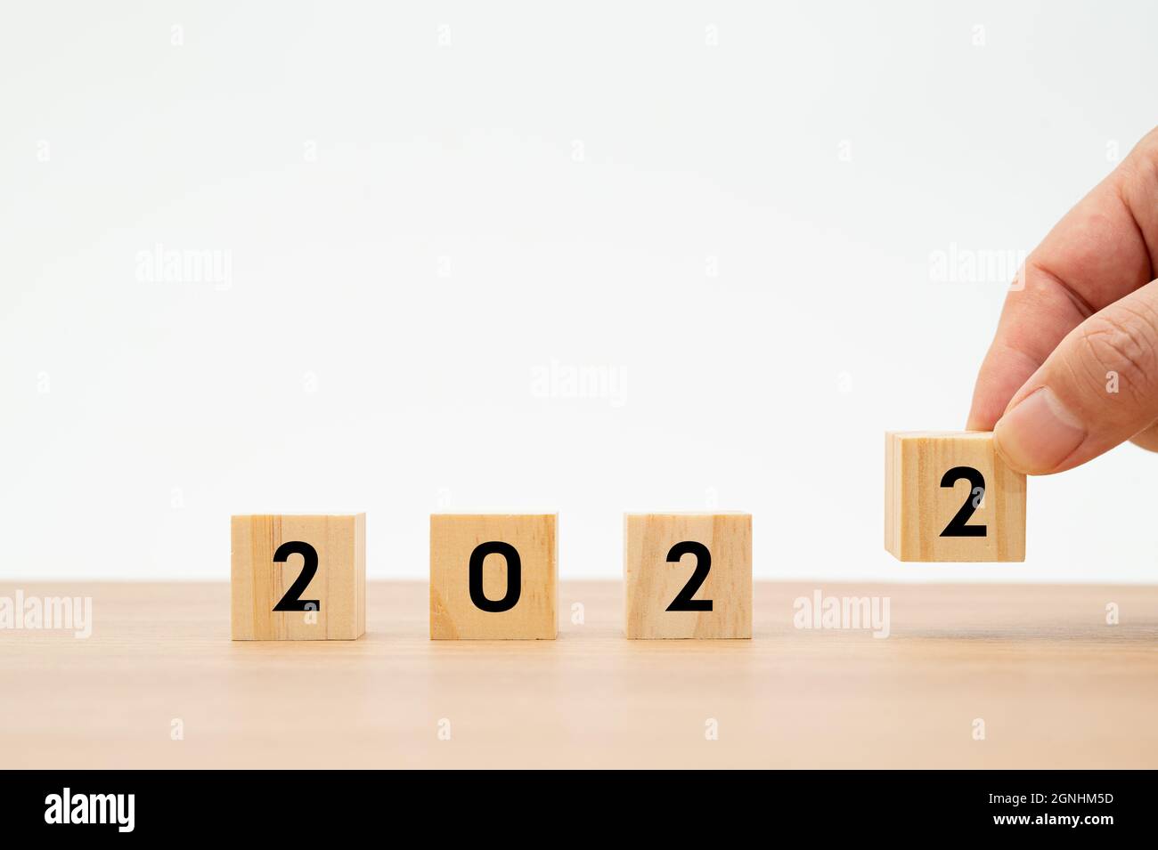 Un uomo che tiene un cubo di legno con 2022 numeri sullo sfondo bianco Foto Stock Un uomo che tiene un cubo di legno con 2022 numeri sullo sfondo bianco Foto Stock