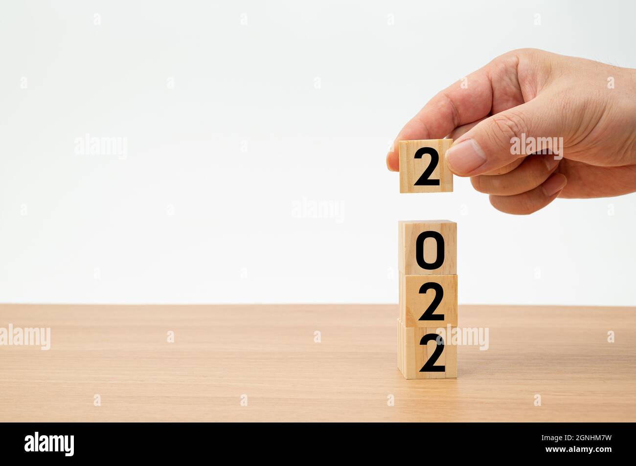 Un uomo che tiene un cubo di legno con 2022 numeri sullo sfondo bianco Foto Stock Un uomo che tiene un cubo di legno con 2022 numeri sullo sfondo bianco Foto Stock