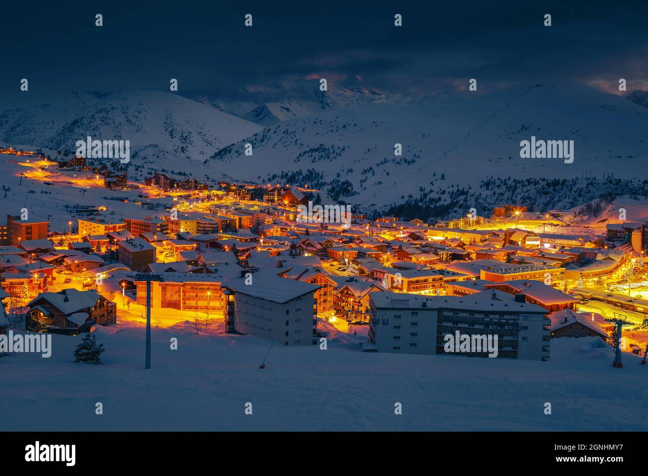 Favolosa stazione sciistica invernale e paesaggio urbano di notte. Famosa destinazione di viaggio e piste nevose di notte, Alpe d Huez, Rodano Alpi, Francia, Europa Foto Stock