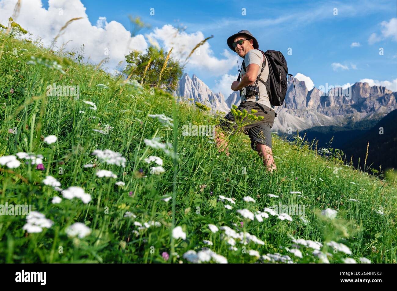 Il fotografo si snoda tra i prati alpini fioriti intorno al villaggio di S. Magdalena, Italia. Splendida scena estiva della Valle di Funes (Villnob) con Foto Stock