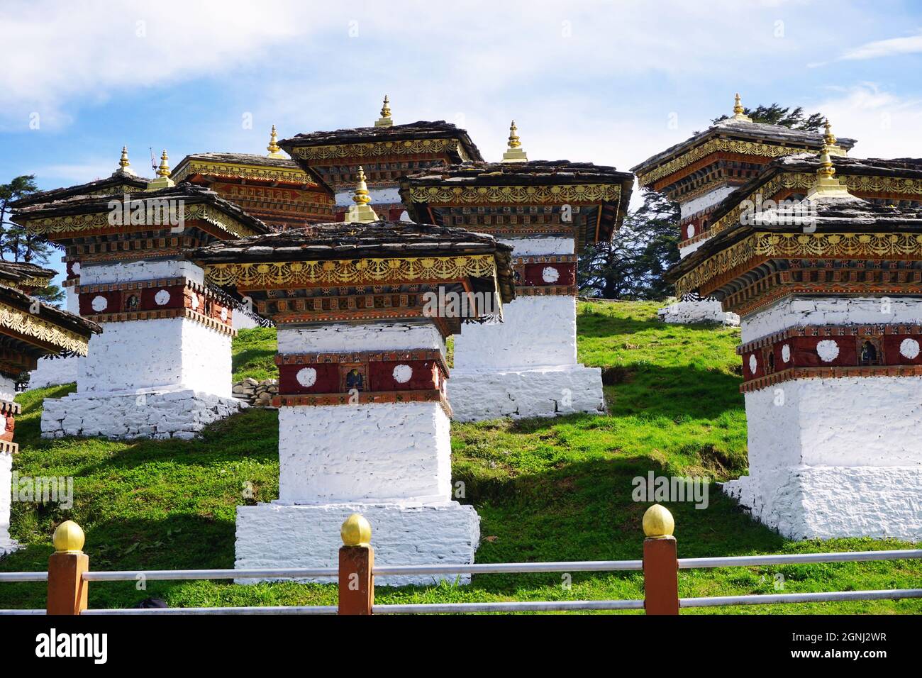 Una vista di alcuni dei 108 Chortens Druk Wangyal identici situati al Passo Dochula di Bhutan sulla strada da Thimphu a Punakha con cielo blu chiaro Foto Stock