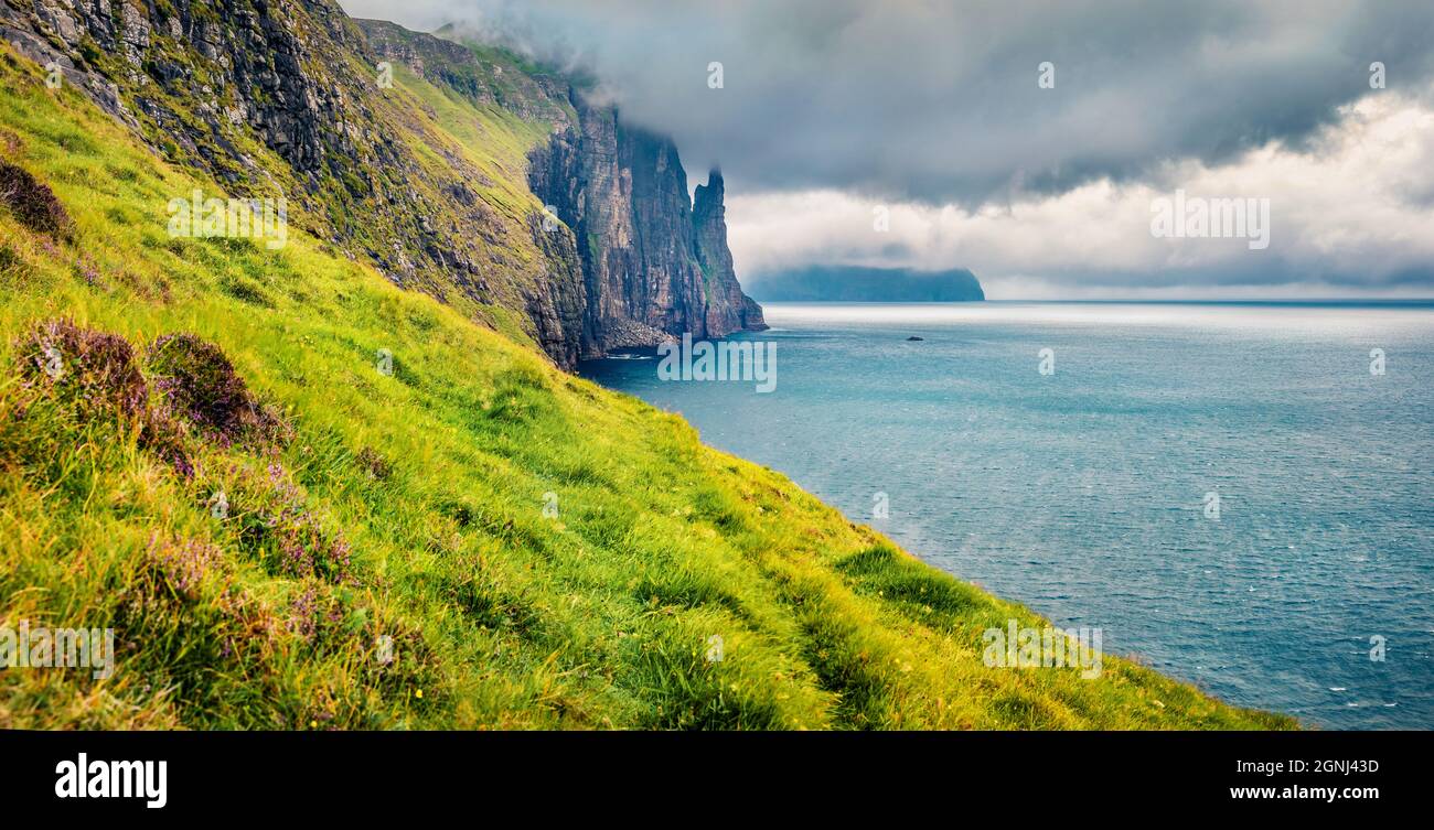 Paesaggio faroese mozzafiato con le scogliere di Trollkonufingen sull'isola di Vagar. Maestosa scena estiva della periferia del villaggio di Sandavagur, Isole Faroe, Kingd Foto Stock