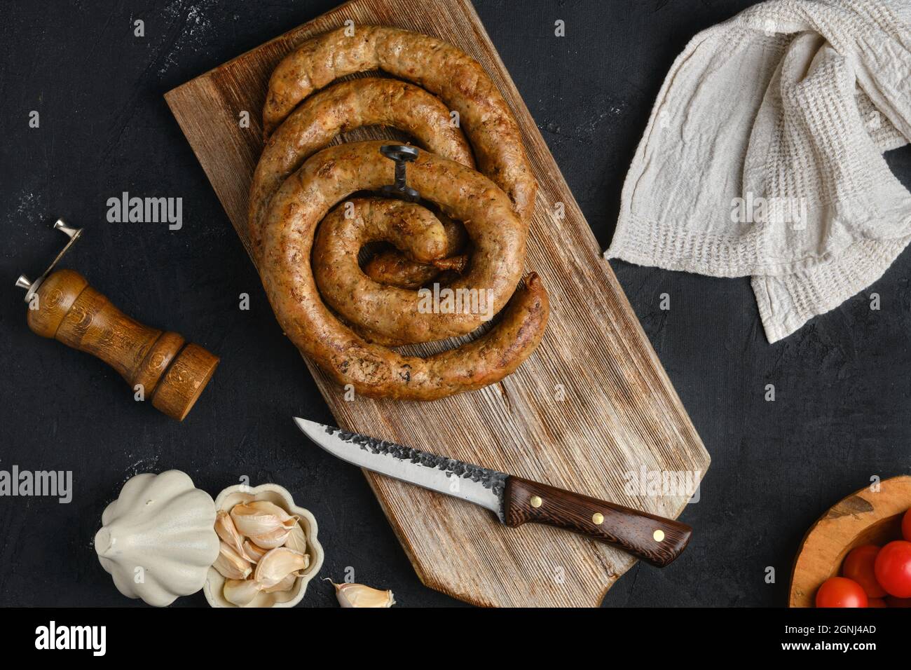 Salsiccia di carne di cavallo con aglio arrotolato su tagliere di legno Foto Stock