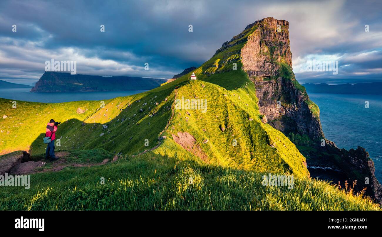 Il fotografo fotografa il faro di Kallur, l'isola di Kalsoy. Incredibile scena estiva delle Isole Faroe, Danimarca, Europa. Maestoso mare di Atlantanti Foto Stock