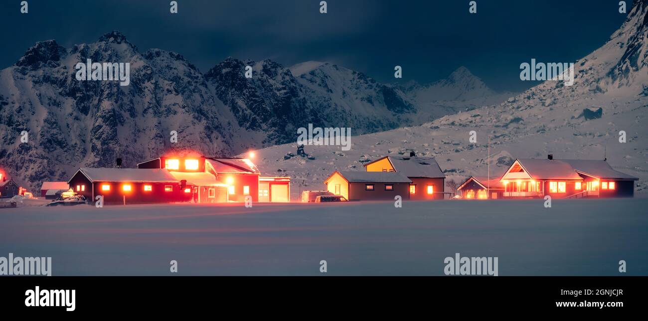 Vista panoramica invernale del villaggio di Utakleiv sull'isola di Vestvagoy. Calda illuminazione serale delle case tradizionali norwagiane. Maestoso paesaggio notturno di Foto Stock