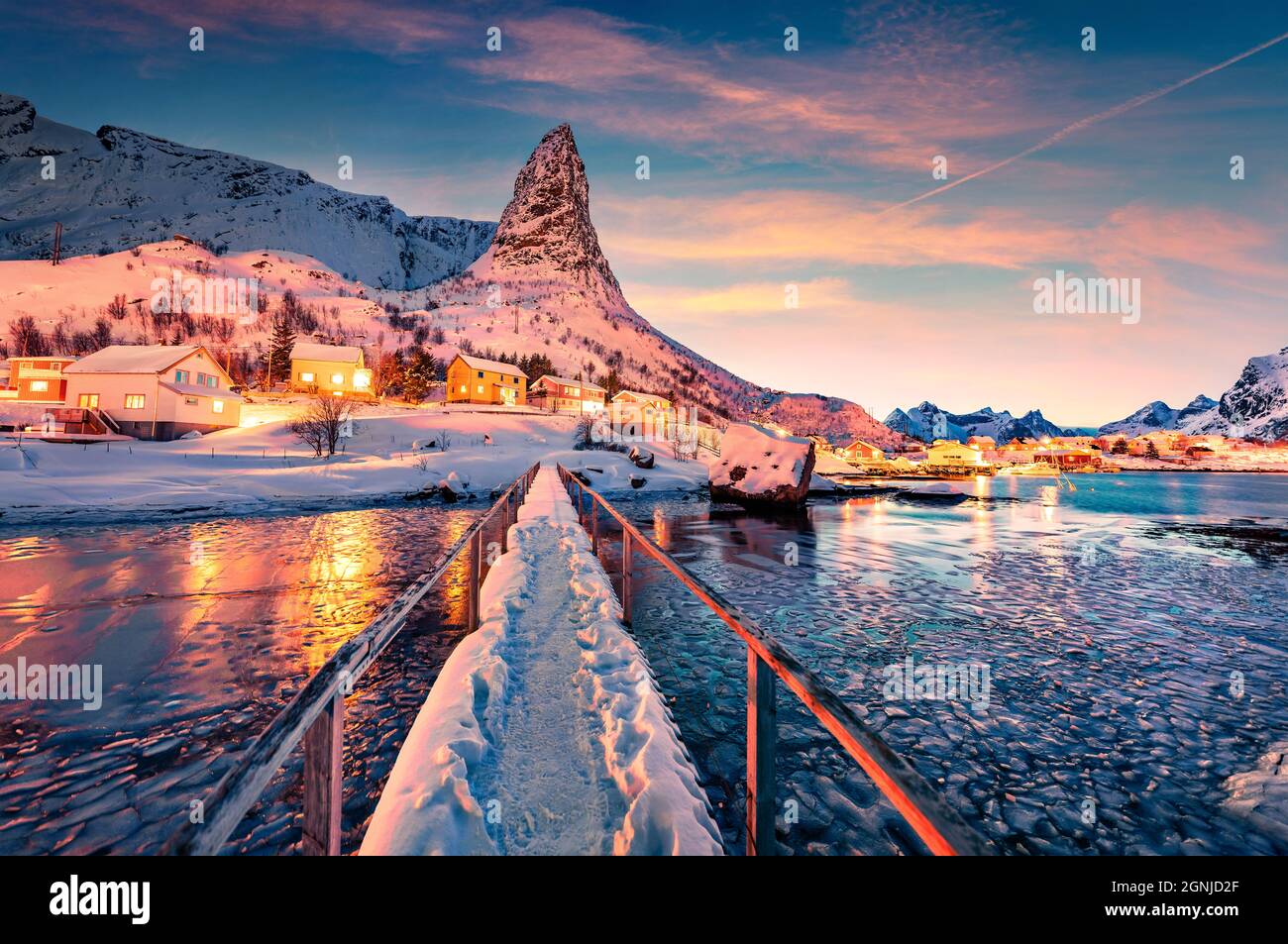 Popolare destinazione turistica - ponte pedonale sopra la baia di Gravdalbukta. Favoloso tramonto sull'arcipelago delle isole Lofoten. Splendido paesaggio urbano serale di Reine t Foto Stock