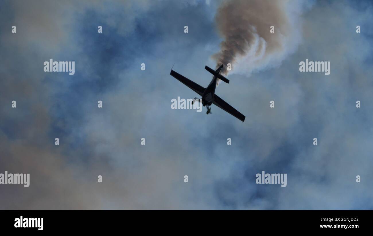 Maribor Airshow Slovenia AGOSTO, 15, 2021 silhouette nera di un aereo aerobatico mentre scende verticalmente immerso nel suo fumo. MX Aircraft MXS di Veres Zoltan Foto Stock