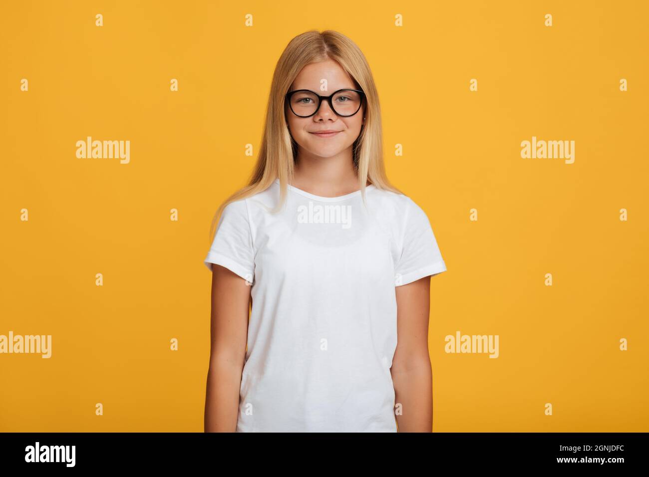 Calma sicura ragazza adolescente europea graziosa in t-shirt bianca e occhiali guardando la macchina fotografica Foto Stock