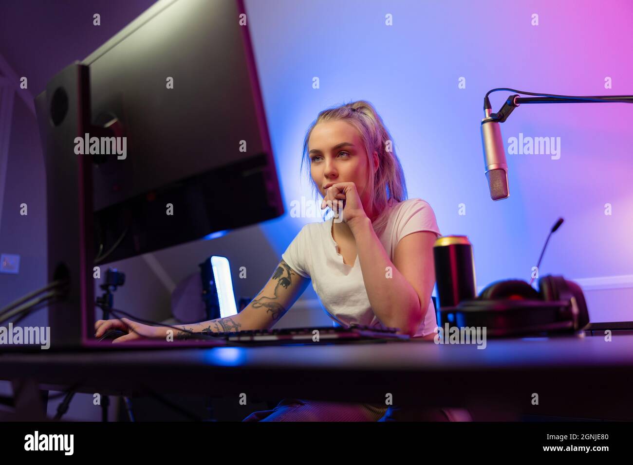 Ragazza gamer professionale dall'aspetto accattivante trasmette in streaming e gioca a un videogioco multigiocatore online su PC Foto Stock