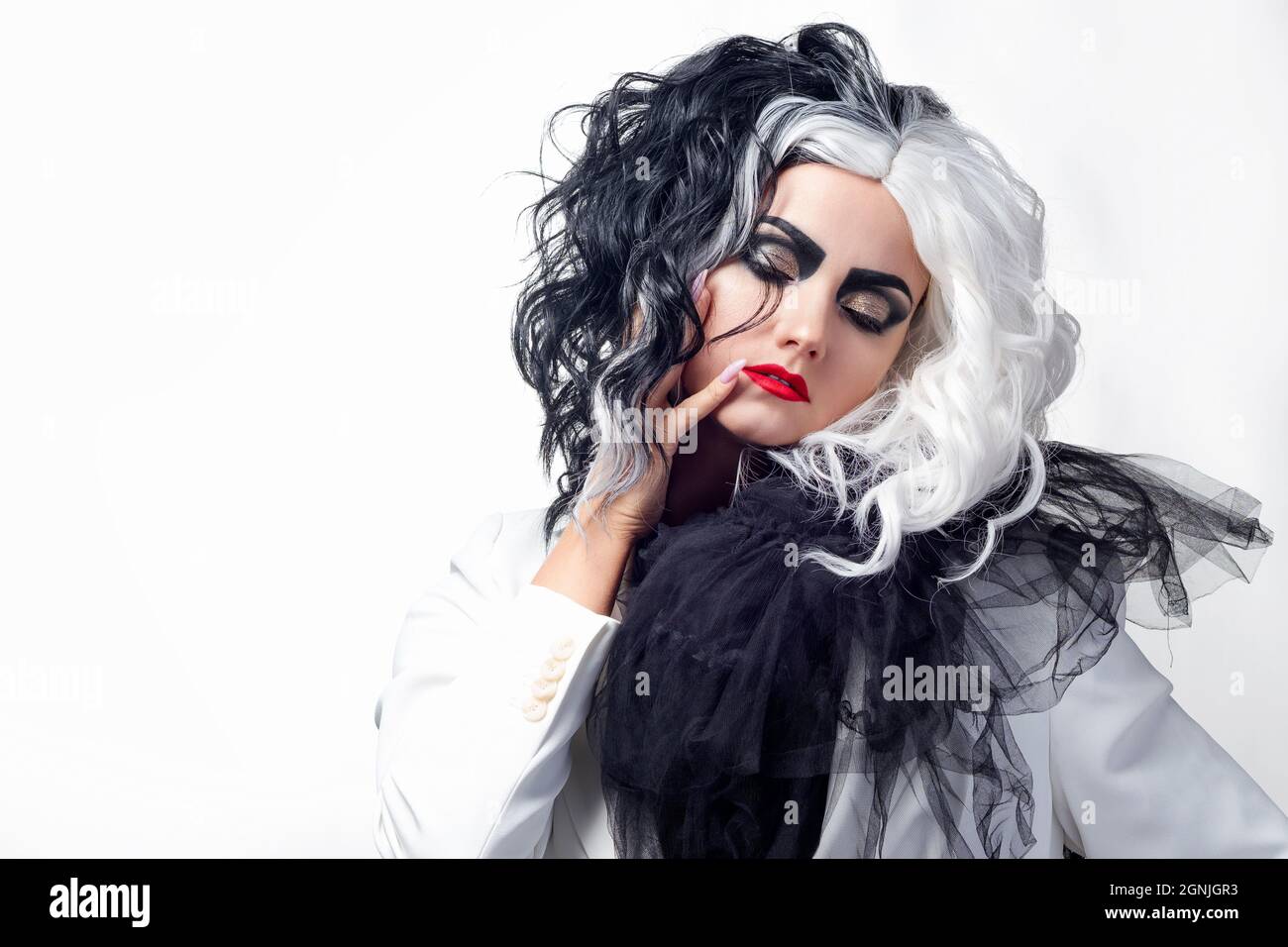Una donna carismatica insolita in un abito bianco e nero con capelli bianchi e neri, un'immagine audace ed elegante di un criminale per Halloween Foto Stock