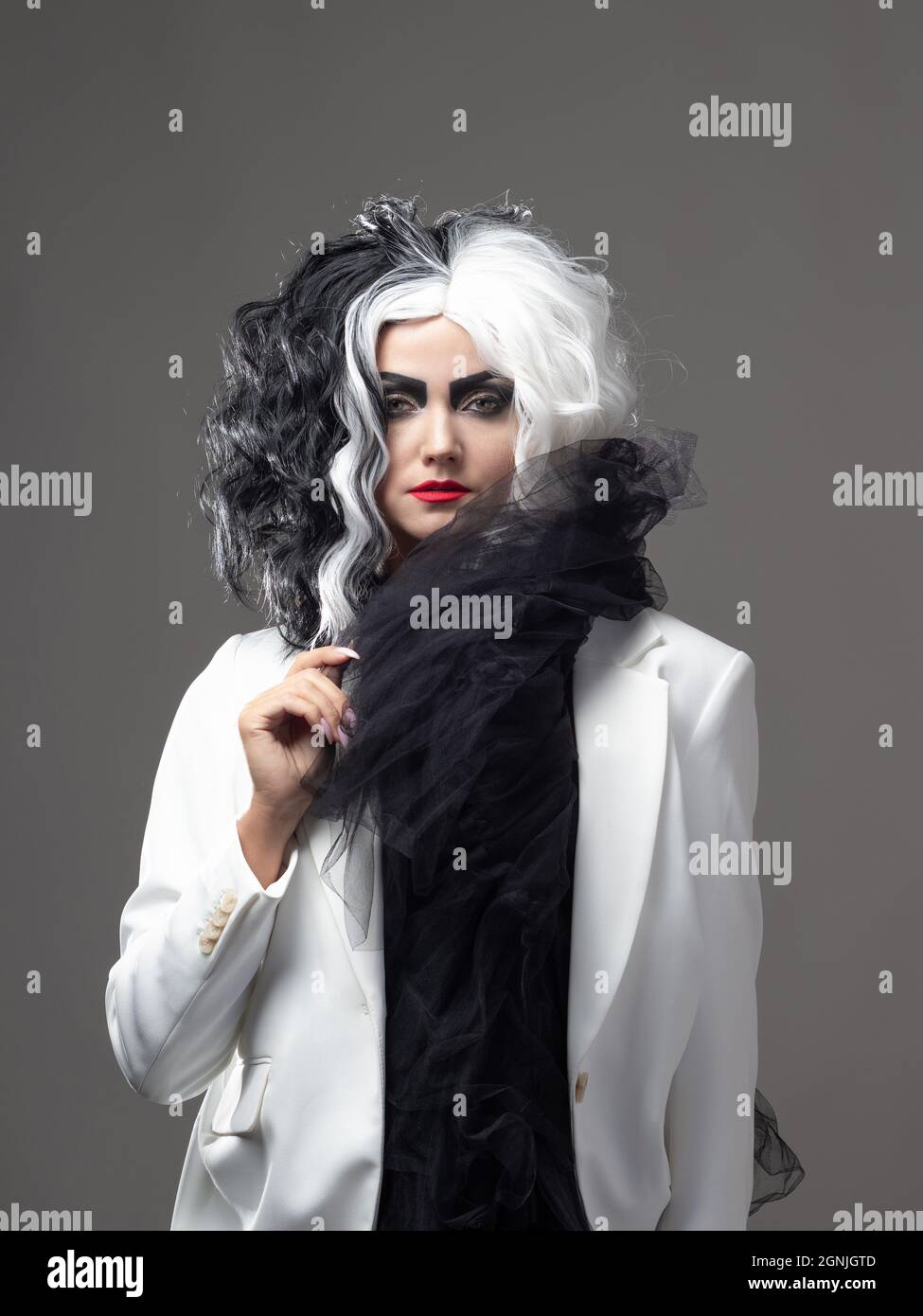 Una donna carismatica insolita in un abito bianco e nero con capelli bianchi e neri, un'immagine audace ed elegante di un criminale per Halloween Foto Stock