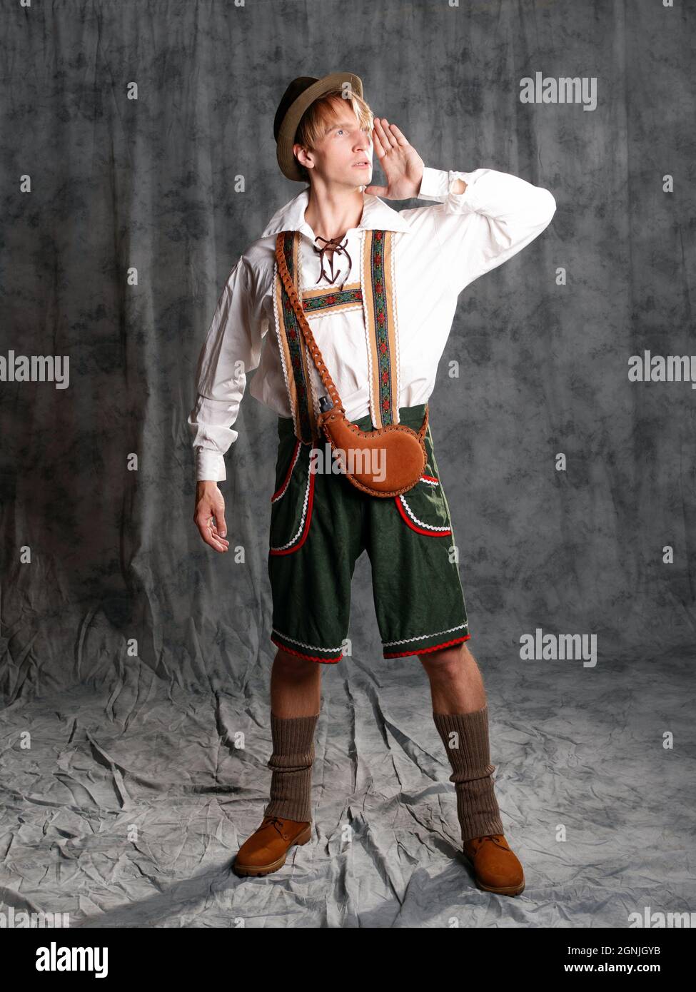 Giovane uomo in abito bavarese nazionale con pantaloncini corti su bretelle  e cappello. Carismatico ritratto bavarese a tutta lunghezza, gridando e  chiamando qualcuno in Th Foto stock - Alamy