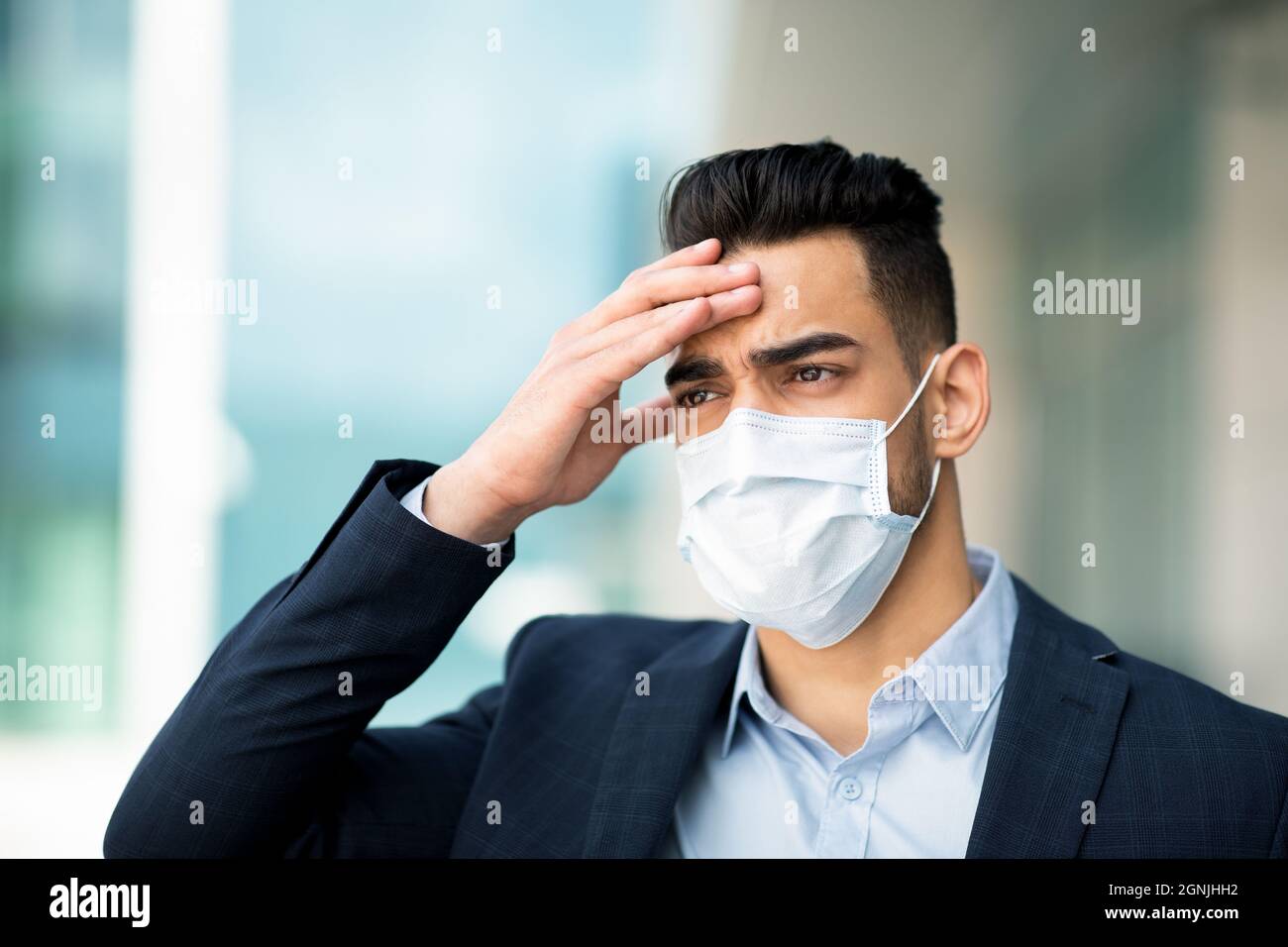 Stressante uomo d'affari medio-orientale in faccia maschera che tocca la testa, fallimento di affari Foto Stock