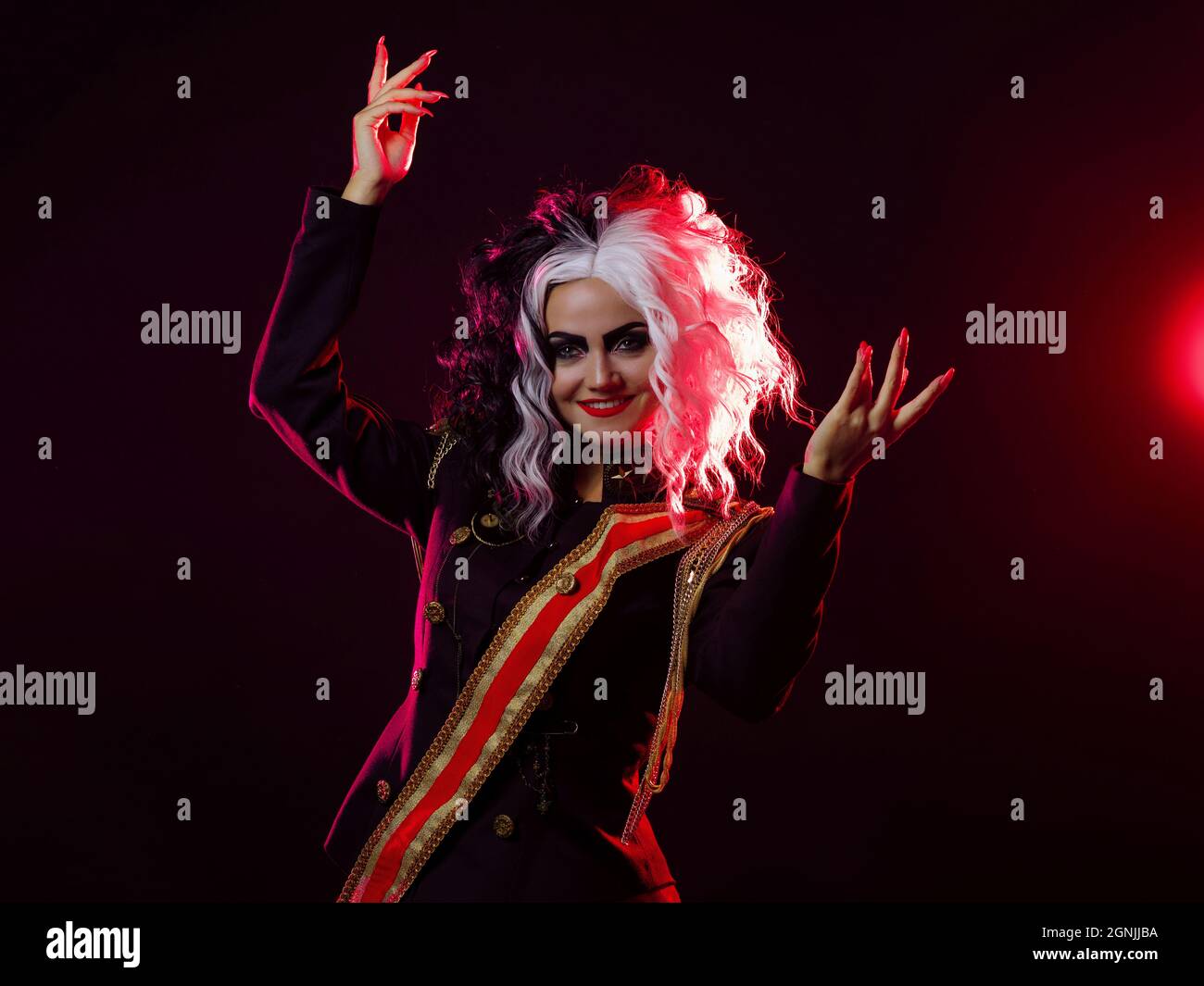 Una donna luminosa e scioccante con un acconciatura in bianco e nero è vestita in una divisa decorata e una gonna piena. Retroilluminazione rossa sul retro. Balli accesi Foto Stock