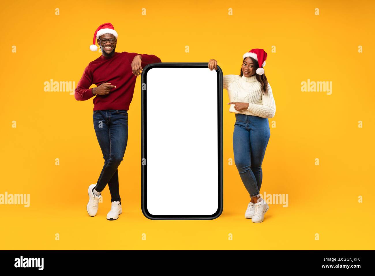 Coppia nera che punta allo schermo del telefono che indossa i cappelli di Santa, studio Foto Stock