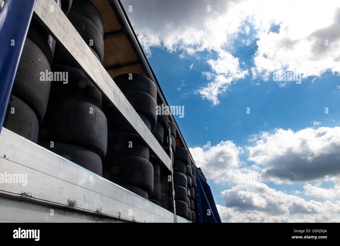 Grande gruppo di gomme da corsa con scelta di variazione slick e pioggia contro cielo blu e nuvole Foto Stock