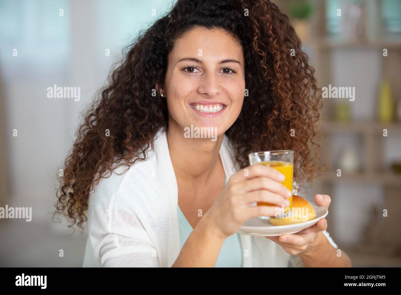 giovane donna che tiene succo d'arancia e un dolce Foto Stock