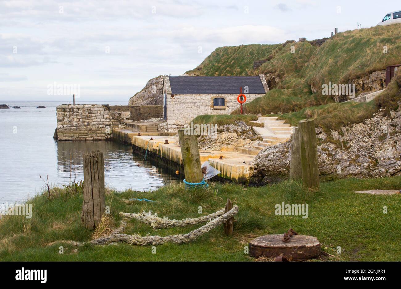 Aprile 2017. Il piccolo porto di Ballintoy sulla costa settentrionale dell'Irlanda del Nord Antrim con la sua antica casa di pietra costruita su una serata in primavera Foto Stock