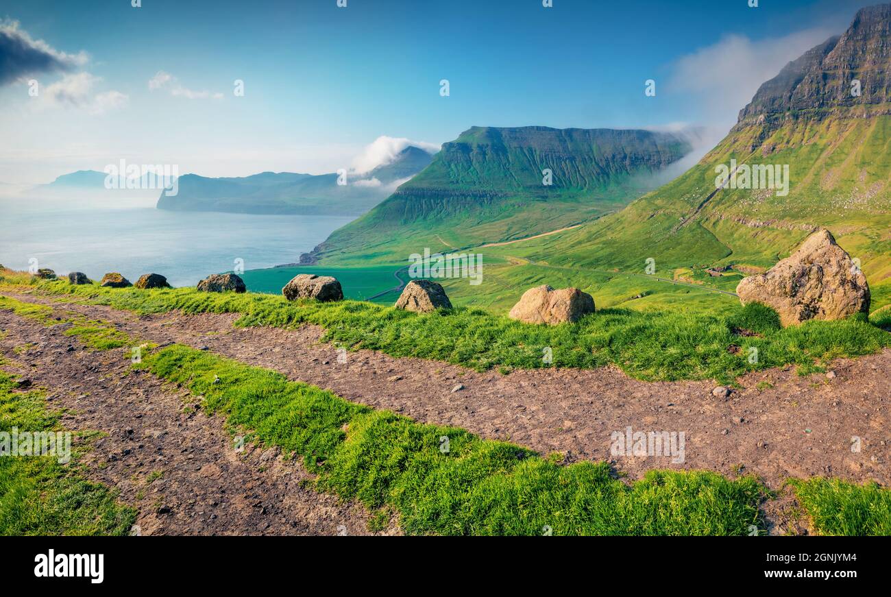 Fotografia aerea del paesaggio. Fantastica vista estiva delle Isole Faroe. Splendida scena mattutina della periferia del villaggio di Sydradalur con vecchia strada di campagna, Foto Stock