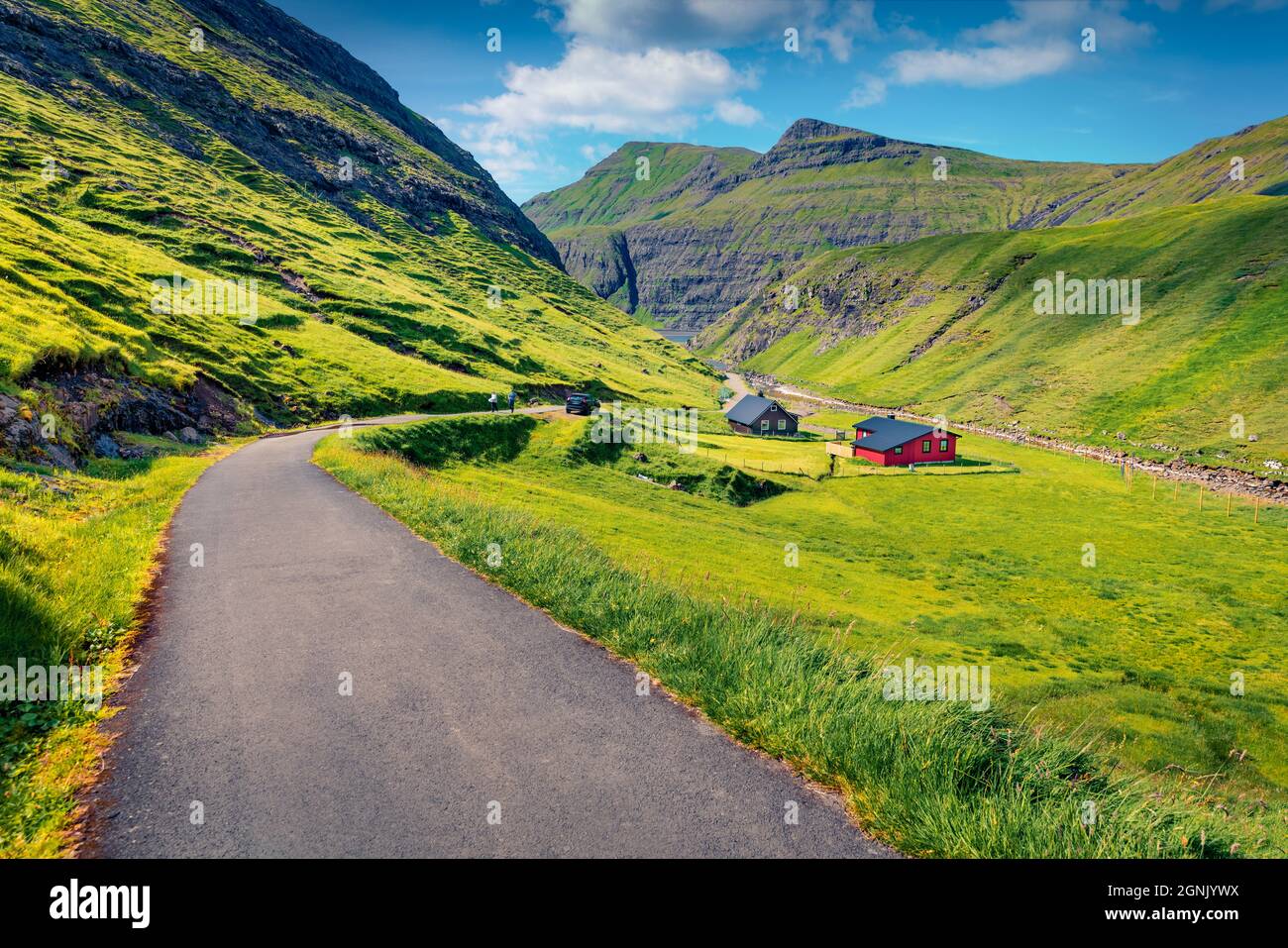 Bellissimo paesaggio estivo. Strada asfaltata vuota nel villaggio di Saksun. Affascinante scena mattutina del canyon di Pollurin, Isole Faroe, Danimarca, Europa. Travelin Foto Stock