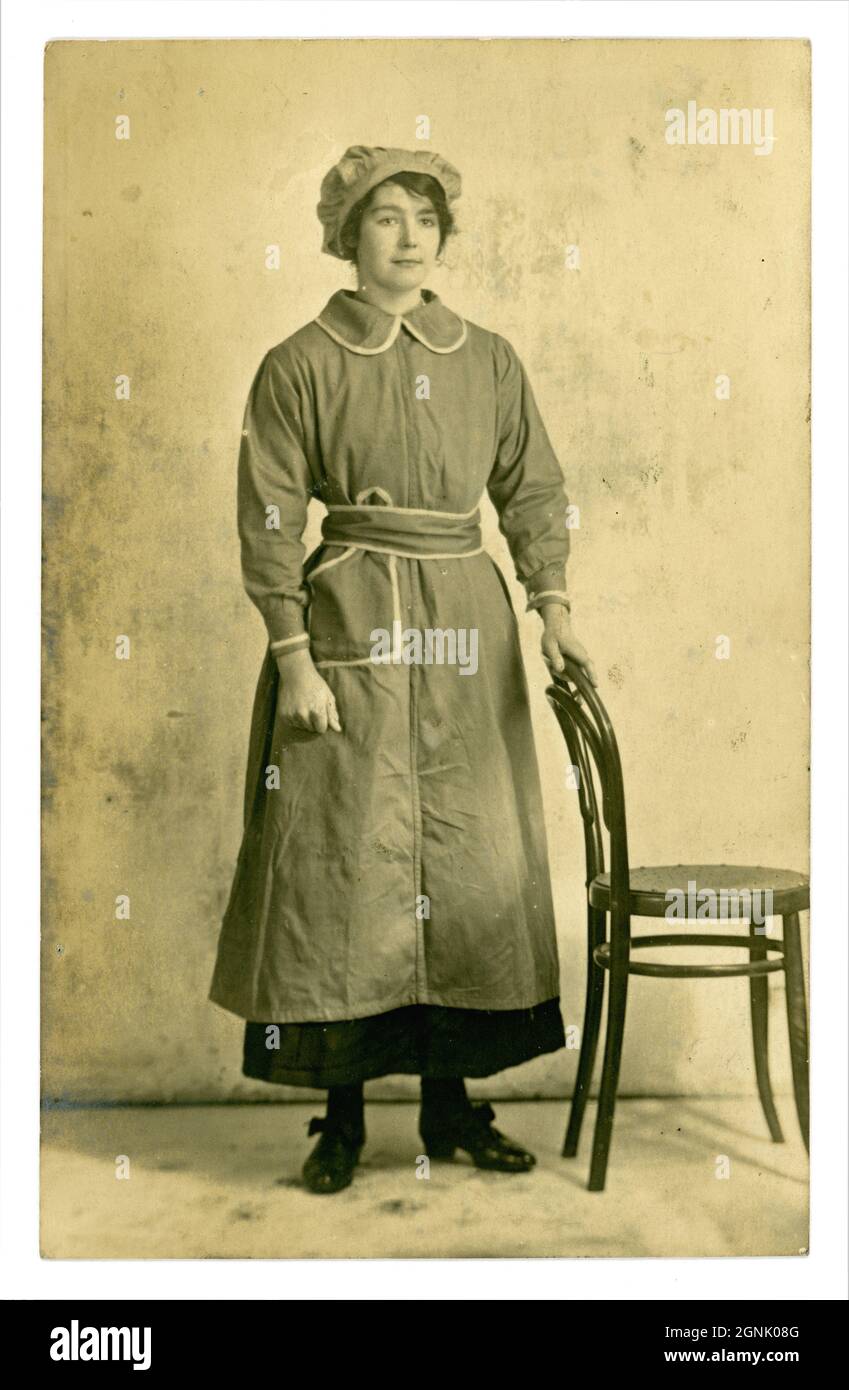 Cartolina originale dell'era della prima Guerra Mondiale del lavoratore di guerra di fabbrica femminile grazioso, che indossa una tunica e cappellino di mob, possibilmente lavoratore di munizioni, circa 1916, luogo sconosciuto, Regno Unito Foto Stock
