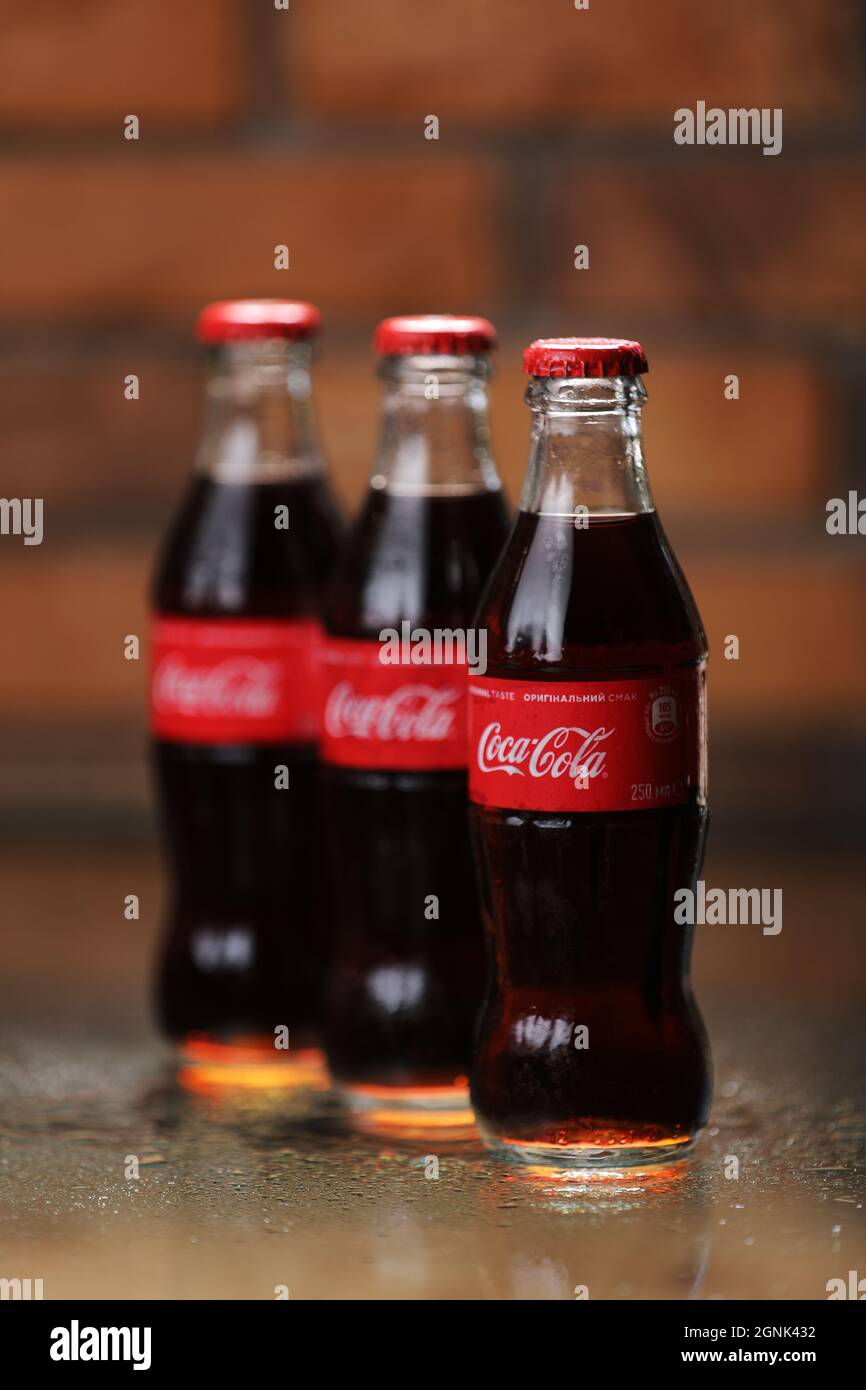 RIVNE, UCRAINA GIUGNO 26 2020: Tre bottiglie di vetro classico di Coca-Cola su sfondo muro di mattoni. Lattine di coca-cola. Foto Stock