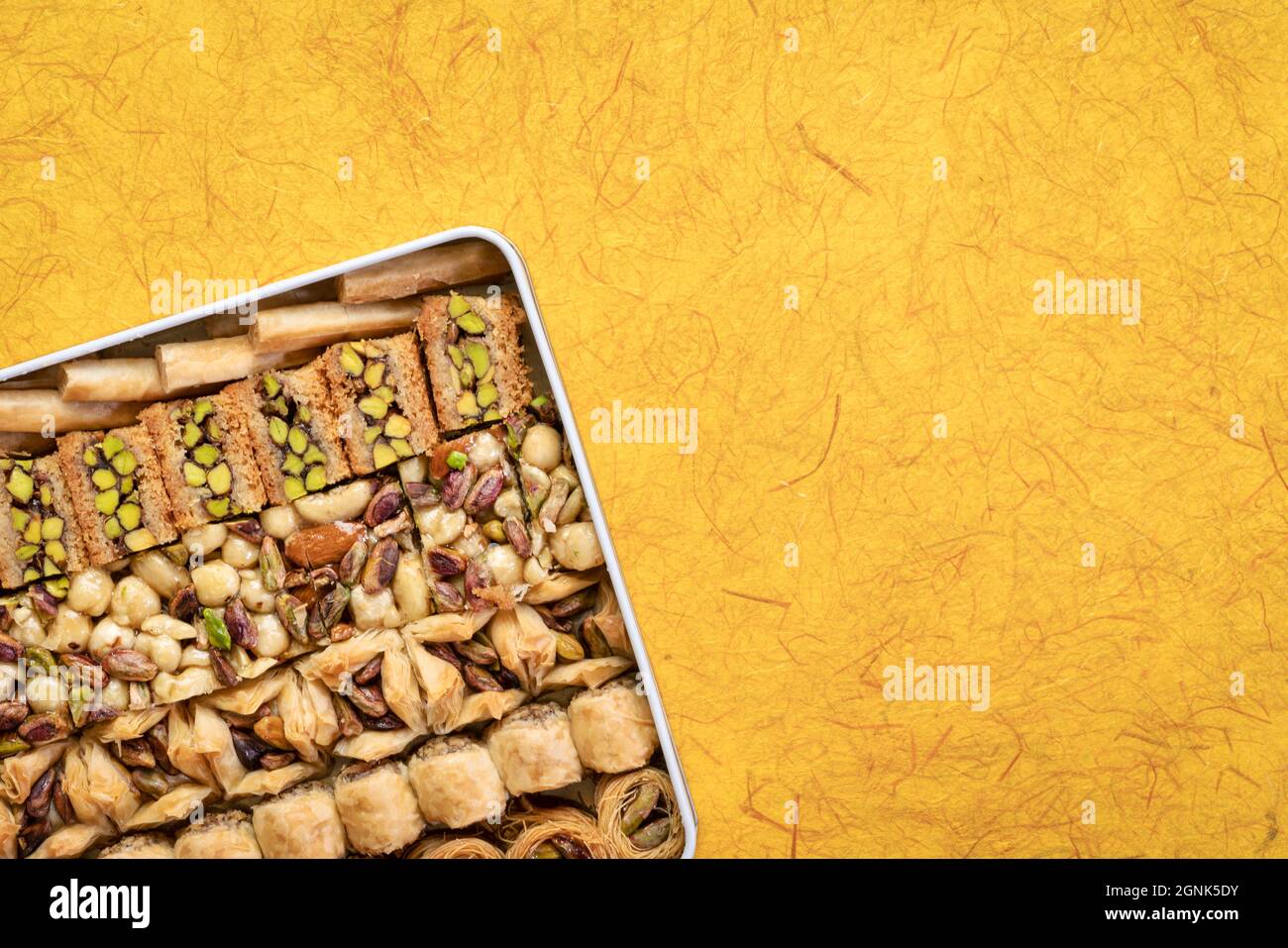 Assortimento di pasticceria turca tradizionale baklava in scatola di stagno contro carta fatta a mano con uno spazio copia, un dessert è anche noto come persiano o leb Foto Stock