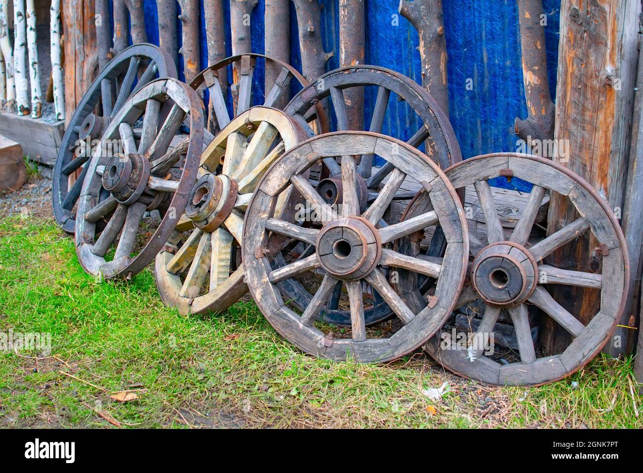 un set, diverse ruote in legno, vecchio, vintage, antico carrello sono in piedi vicino al capannone del villaggio Foto Stock