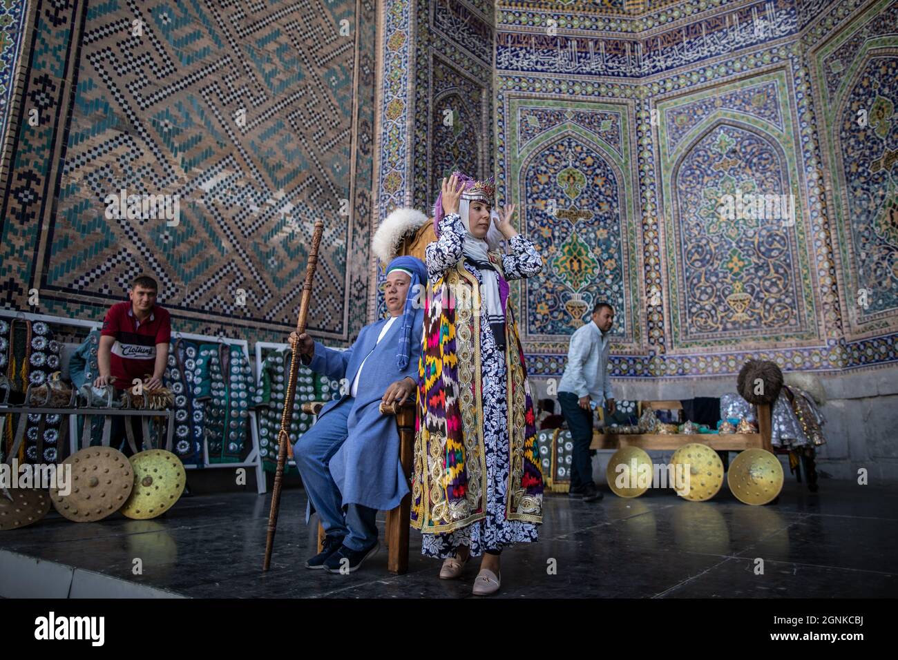 26 settembre 2021, Uzbekistan, Samarcanda: Gli uzbeki indossano abiti tradizionali per una foto ricordo al punto di riferimento storico del Registan a Samarcanda. Il Registan era una piazza pubblica e un centro dell'antica Samarcanda durante l'Impero Timuride, usato per proclami reali, annunciati da blasti su enormi tubi di rame ed esecuzioni pubbliche. Foto: Oliver Weiken/dpa Foto Stock
