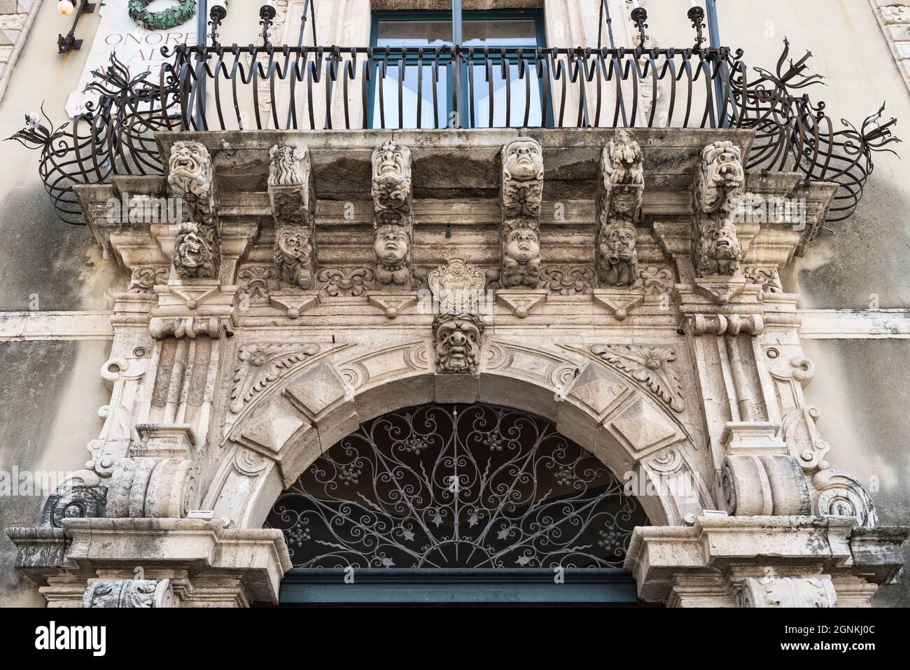 Maschere grottesche scolpite sopra l'ingresso del Palazzo Municipale barocco 18c, Piazza Duomo, Acireale, Sicilia, Italia Foto Stock